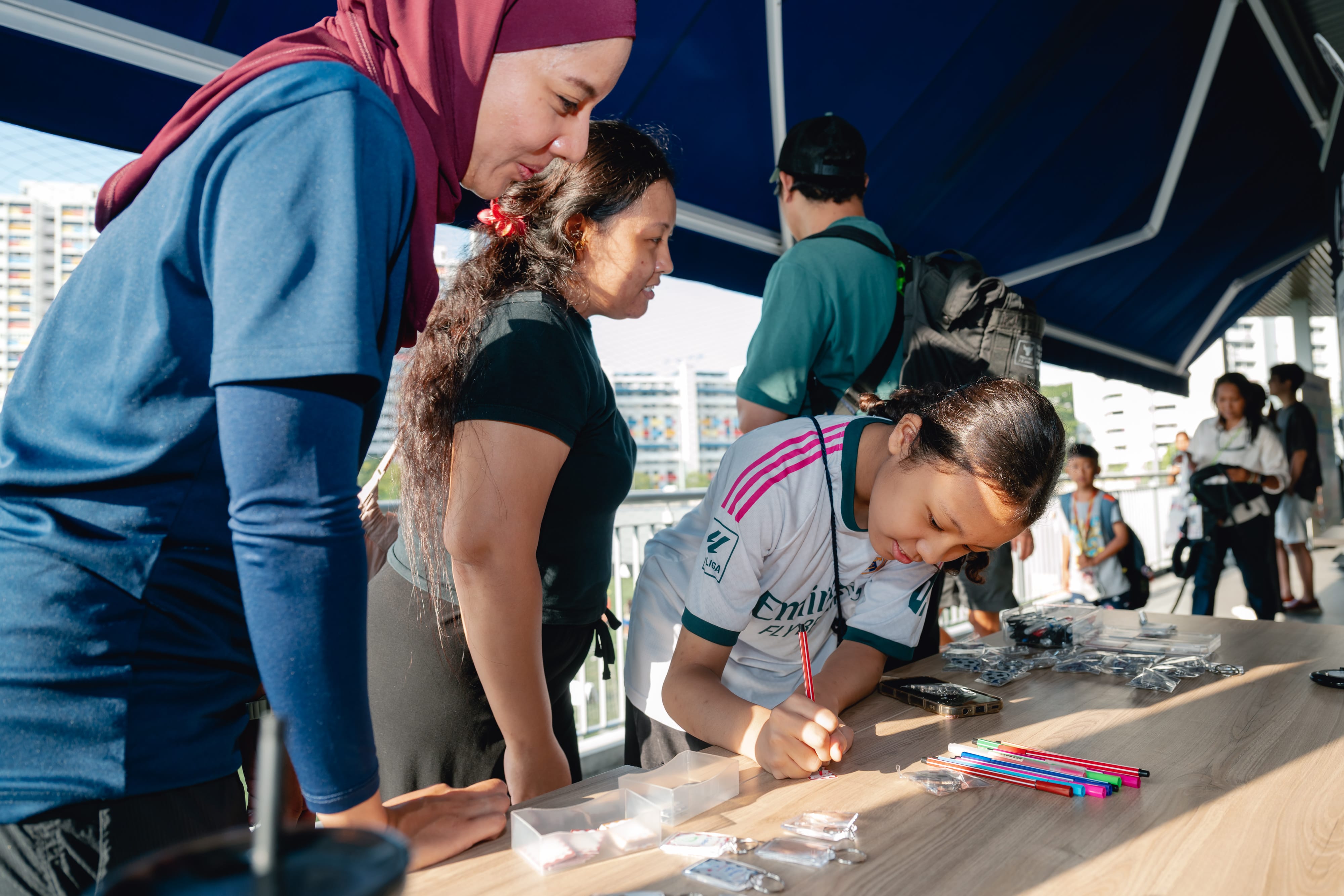 A diverse group of individuals engaged in conversation while standing around a table filled with pens and pencils.
